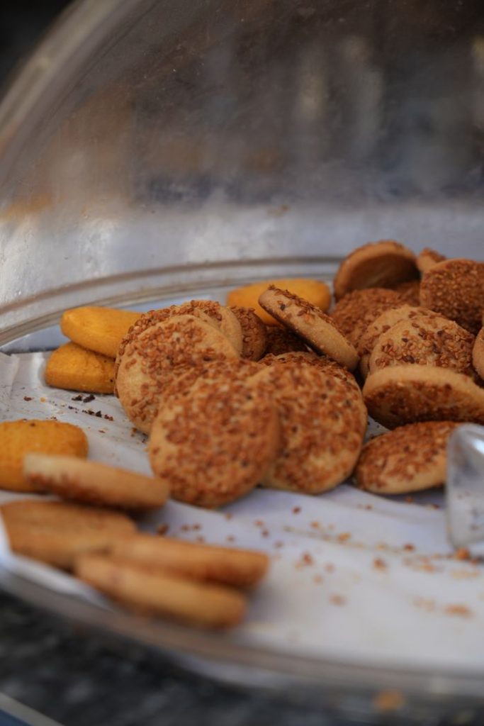 A selection of delicious cookies with sesame seeds and coconut flakes in a bakery display case.